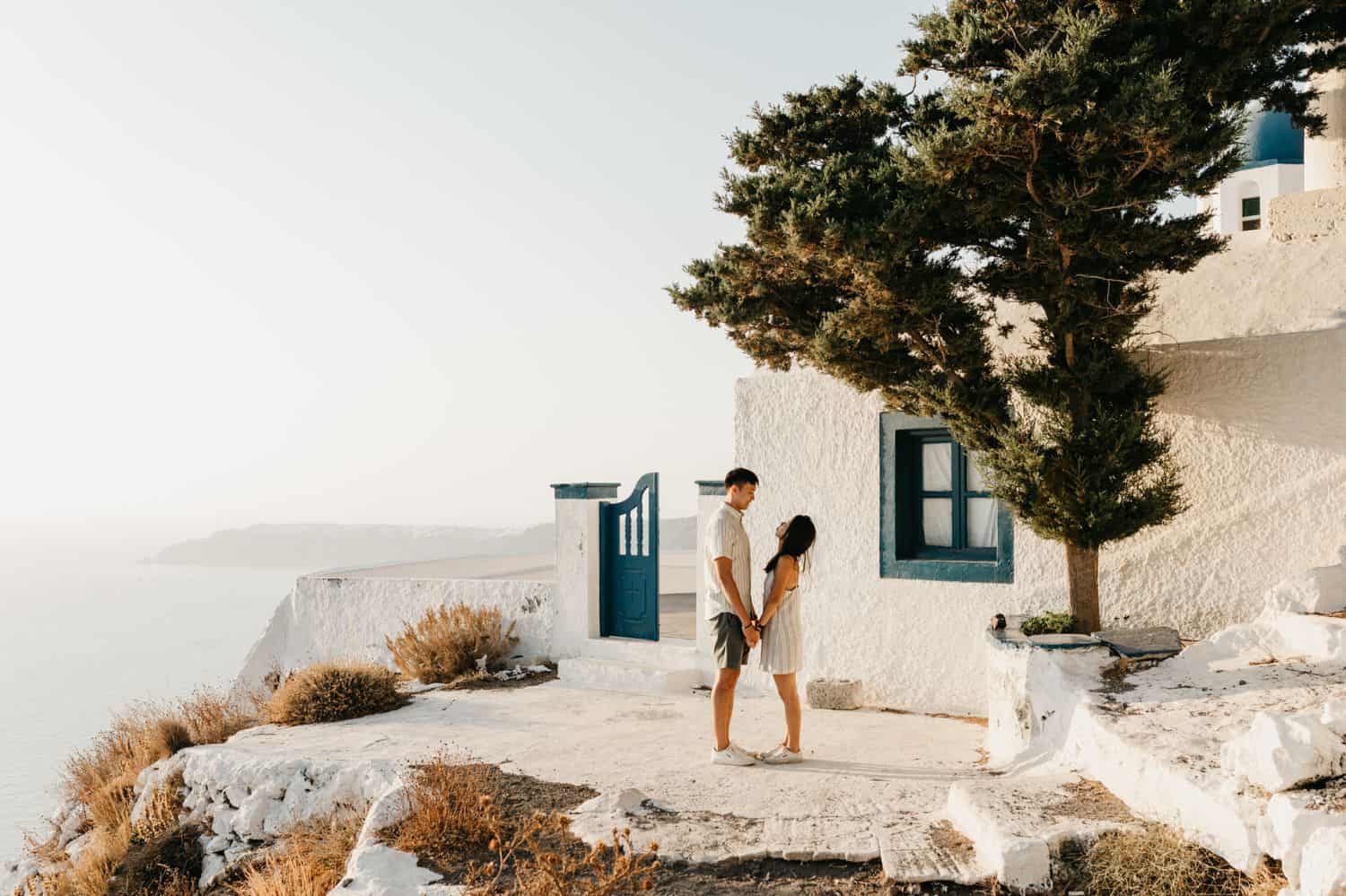 A couple stands on a cliff in Greece