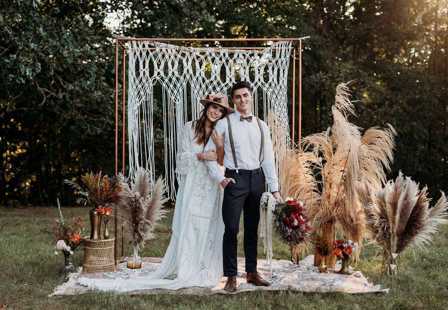 Boho bride and groom pose in front of a macrame backdrop