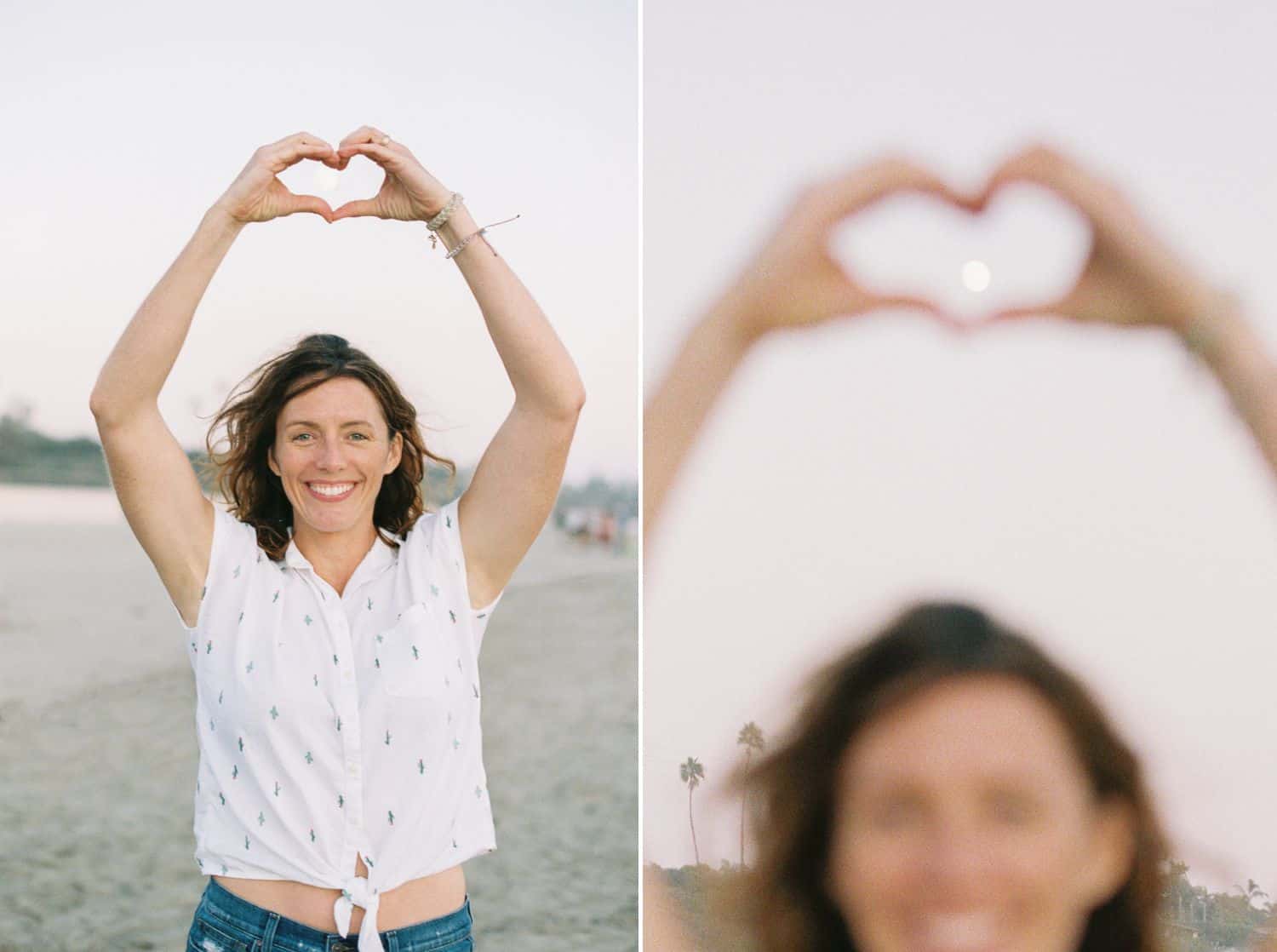 A woman on the beach makes a heart shape with her hands