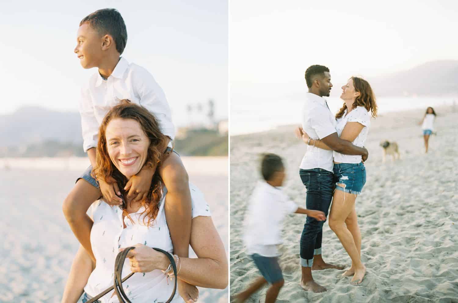 A little boys sits on his mom's shoulders looking out over the ocean. A man holds his wife close as their children and dogs run around them.