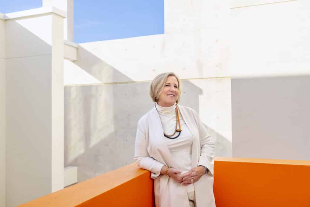 older woman in front of orange wall