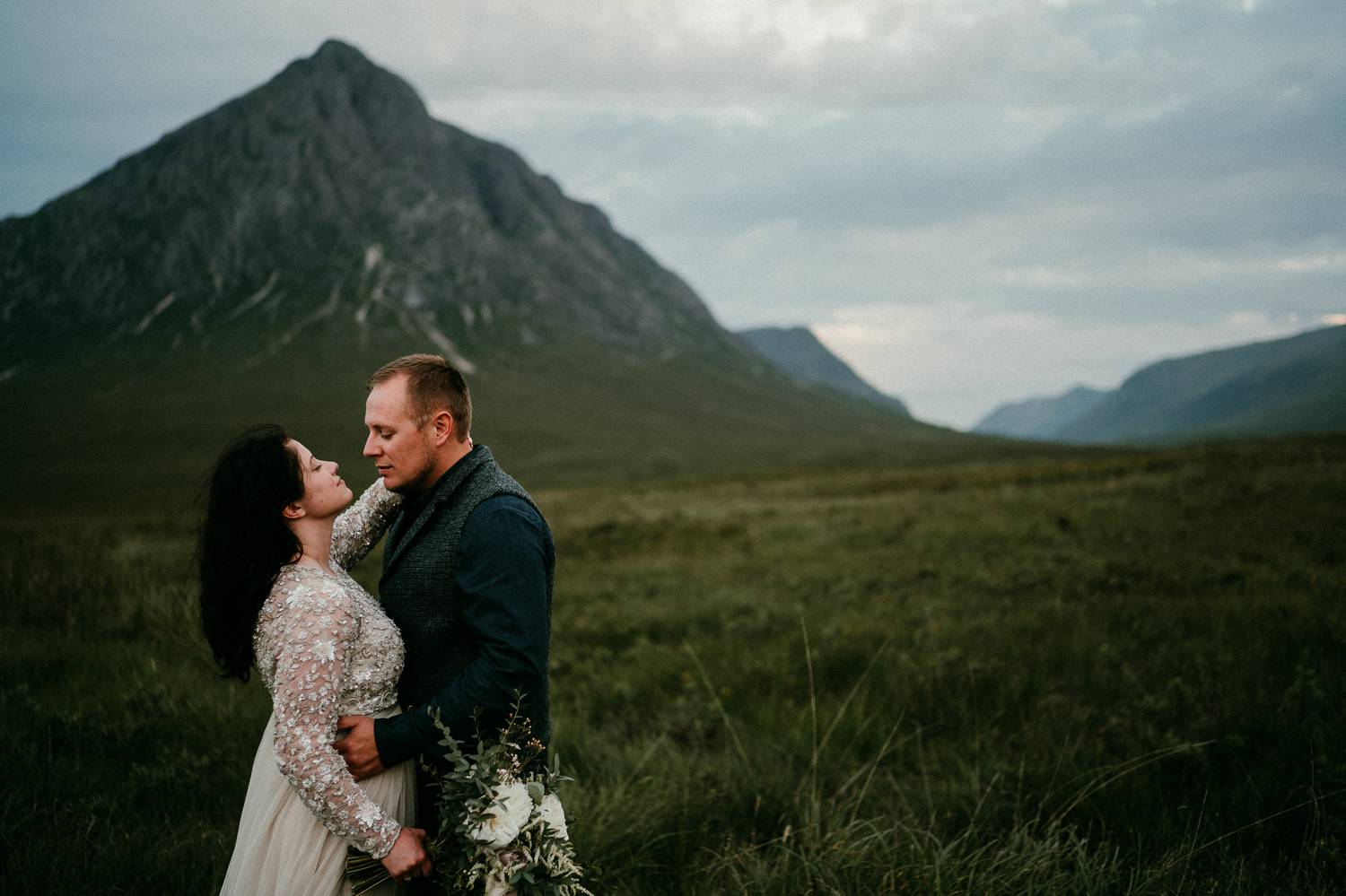 A bride and groom gaze into one another's faces in the shadow of a tall Irish mountain. Photographed by Rob Dight, who began selling photography prints to ensure his clients would always have premium quality products.