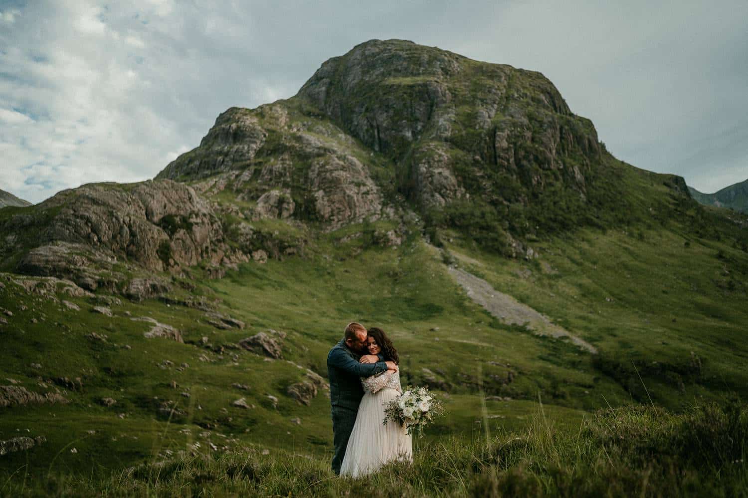 A bride and groom embrace on the wide, green hills of Ireland. Photograph by Rob Dight.