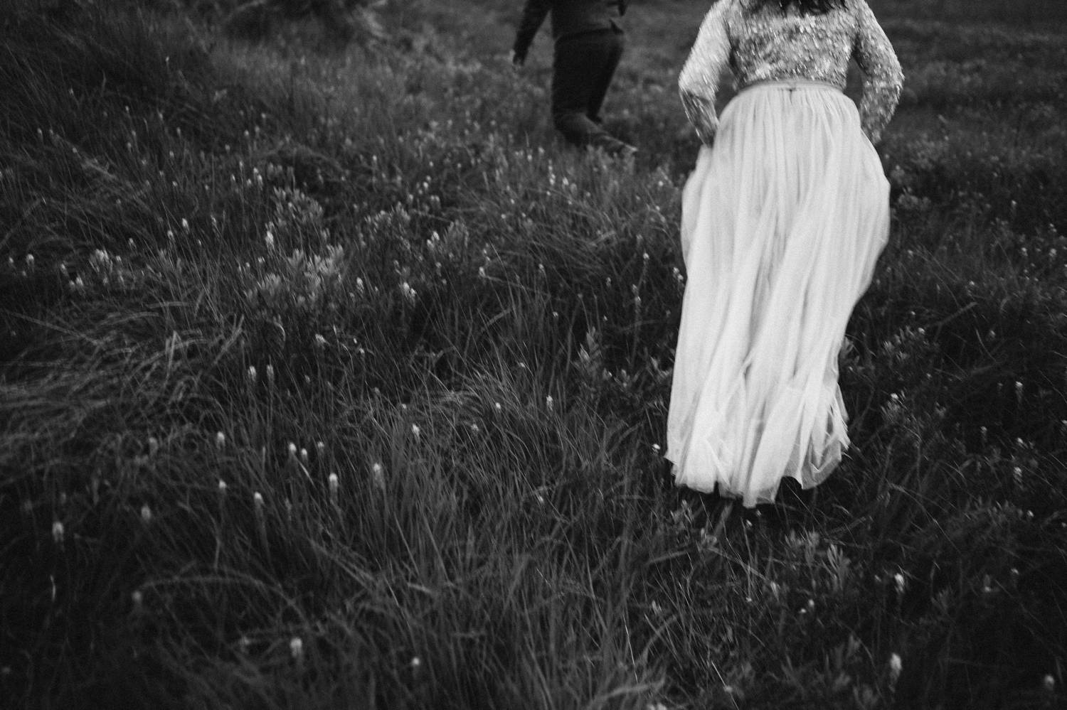 This black and white photo shows of a bride's flowing train as she climbs a grassy hill in Ireland. Photograph by Rob Dight.