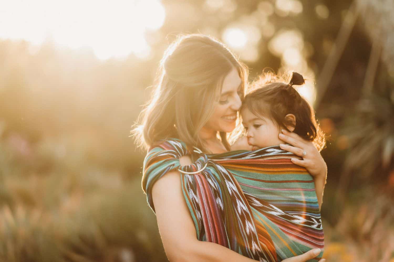 A mother holds her toddler in a wrap