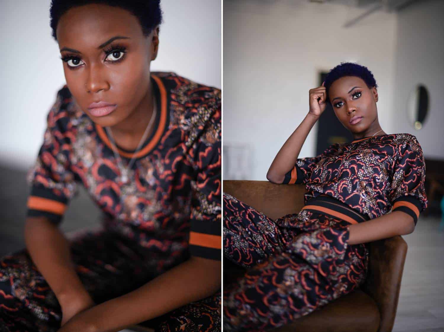 Two side-by-side photos depict a Black woman with closely-cropped hair seated in a window-lit studio. In the first photo, she leans forward on her knees. In the second photos, she leans back in her chair with one hand in her pocket and the other hand propping up her head. She wears a silk jogging suit crafted from a silk floral fabric with orange and black-striped trim.