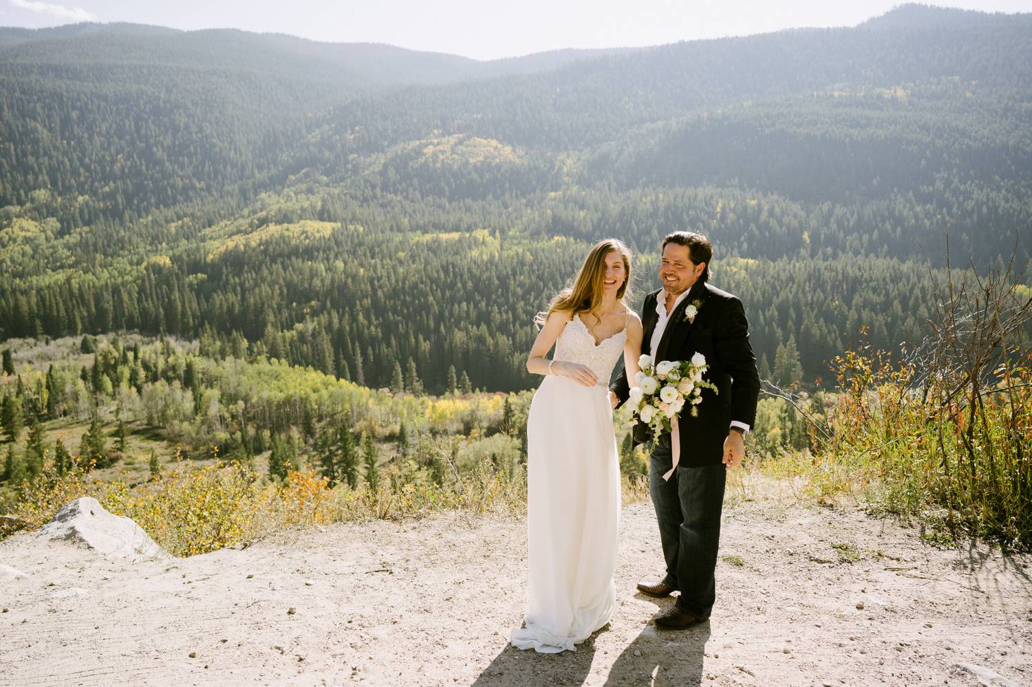 Customer Loyalty: By Nick Sparks, a bride and groom stand close together laughing as the Denver hills rise behind them.