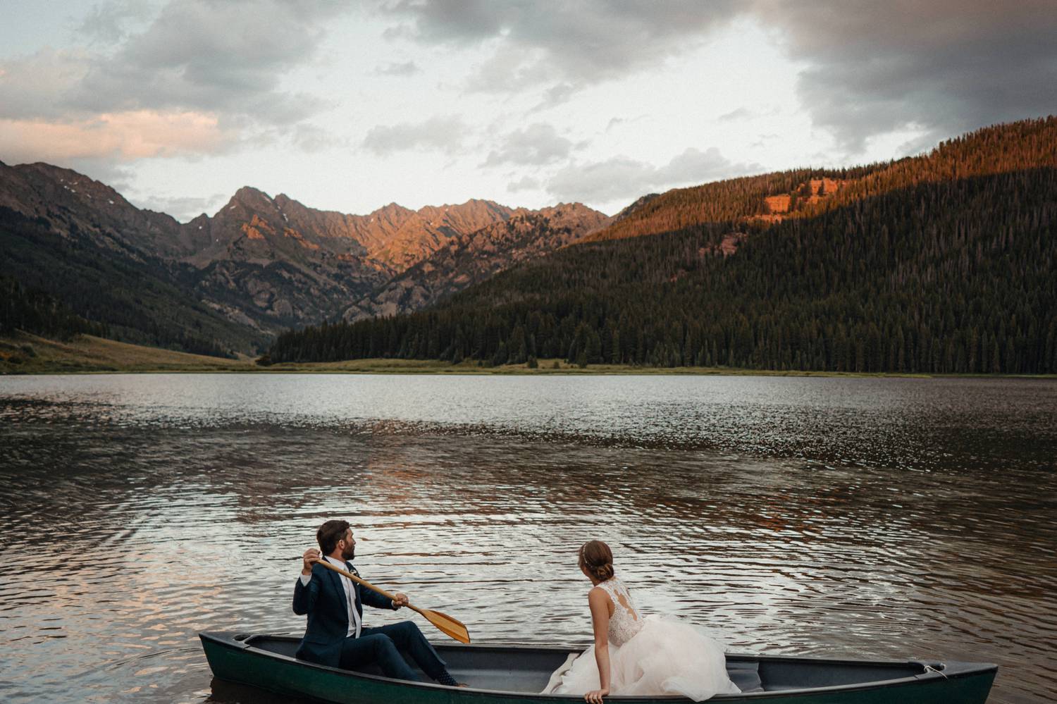 Customer Loyalty: By Nick Sparks, a bride and groom row across a flat lake in the shadow of huge Colorado mountains.