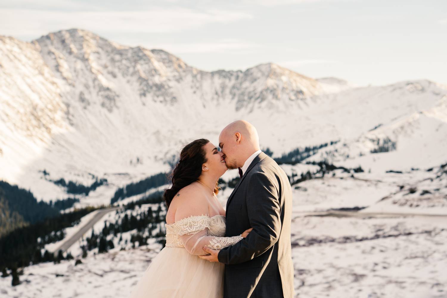 Customer Loyalty: By Nick Sparks, a bride and groom kiss in the foreground while the snowy Colorado mountains loom behind them.