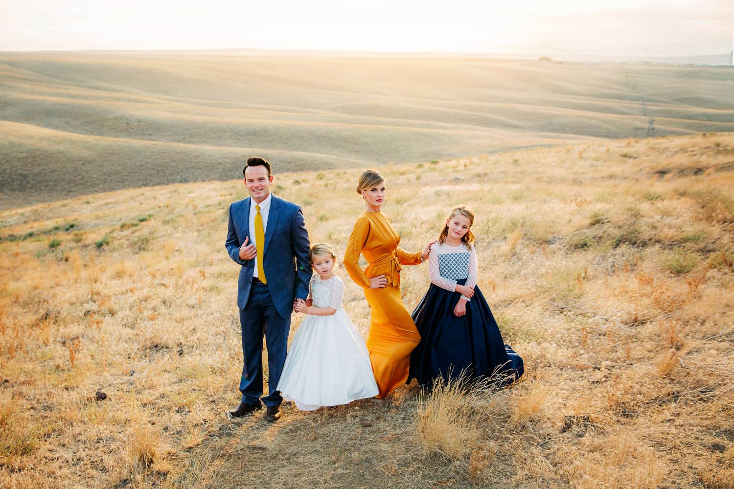 A family with special needs children poses for portraits in a field at dusk.