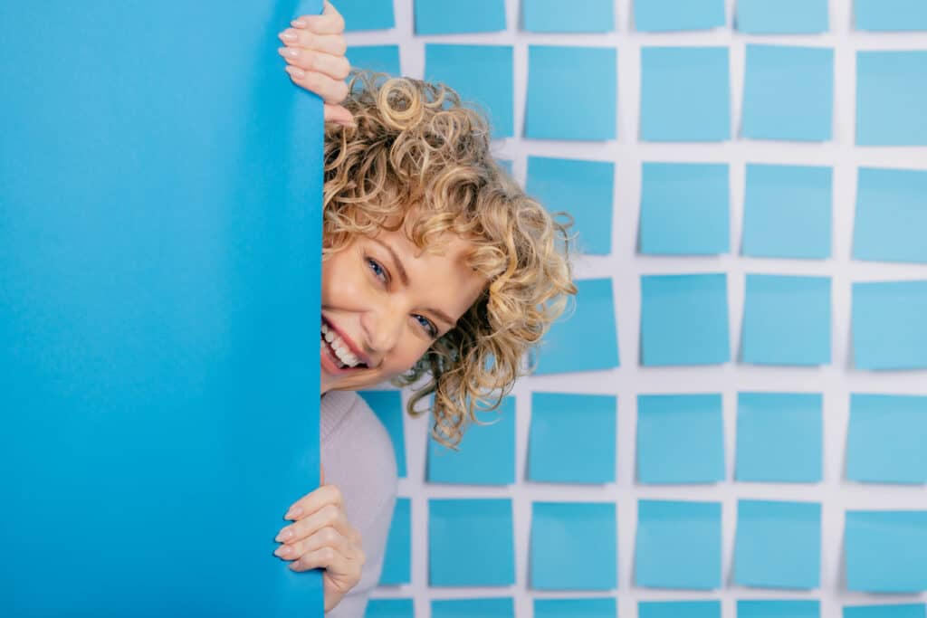 woman peaking in front of blue wall