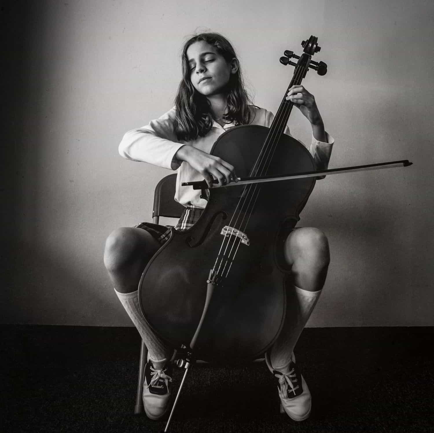 Black and white photograph of a young girl playing the cello. By Kate T. Parker for Strong is the New Pretty