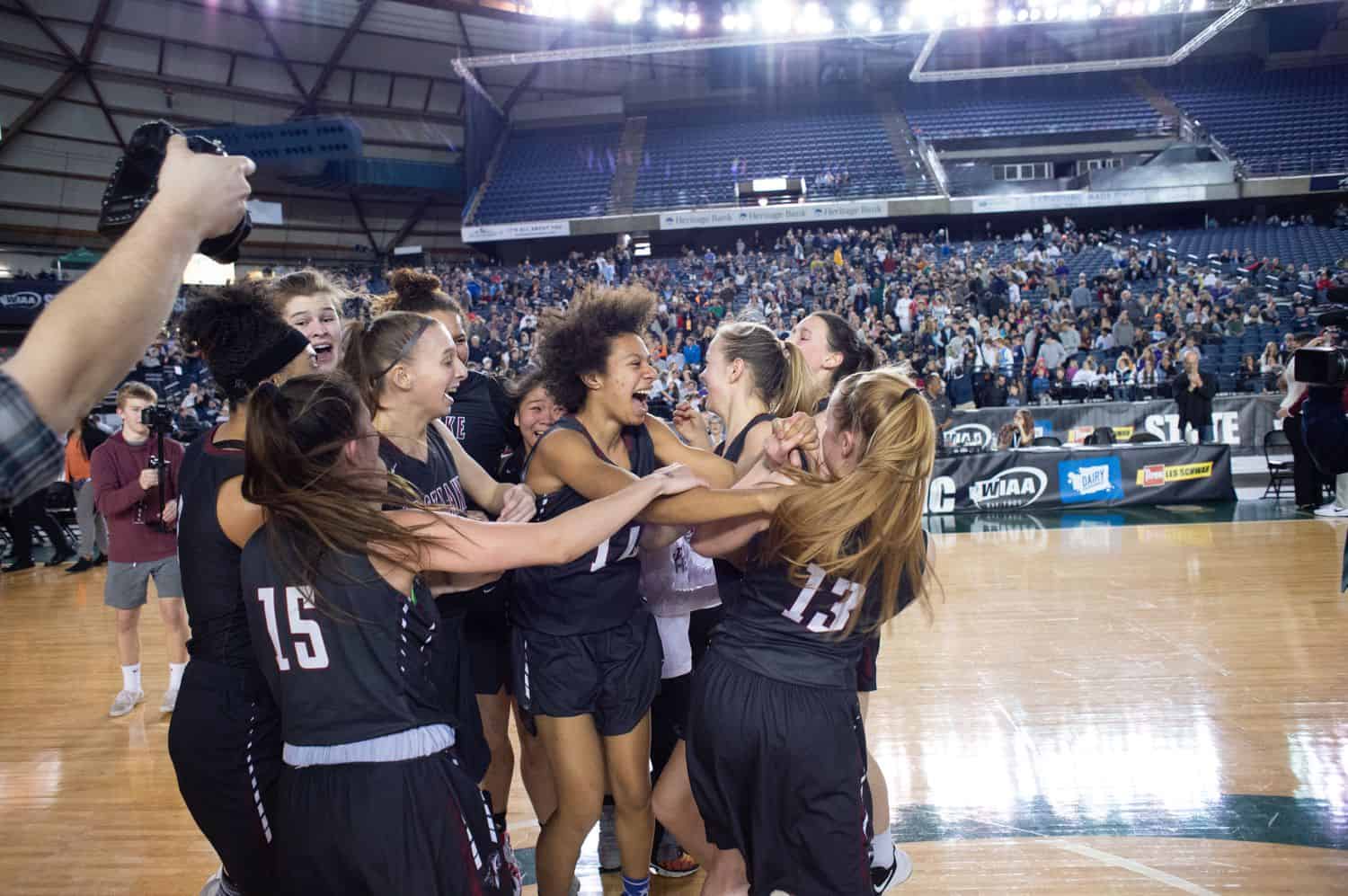 A group of high school girl basketball players celebrate their win on the court