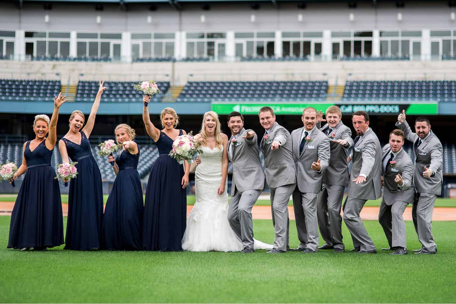 A wedding party strikes a pose on a baseball field.