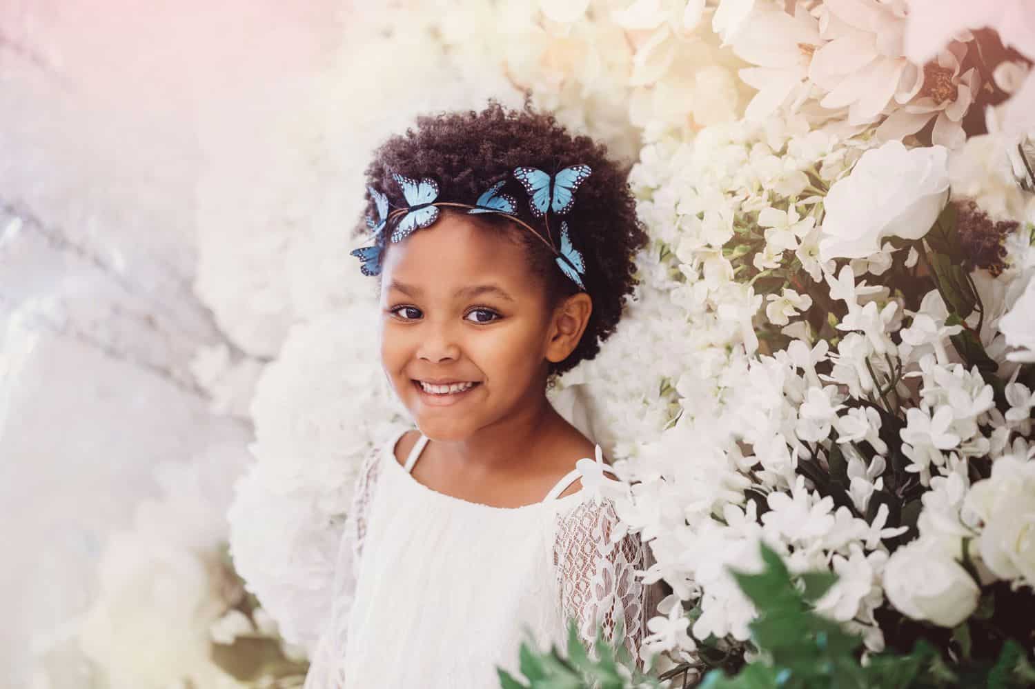 Little girl photographed for Michael's Challenge photo project amid white flowers.