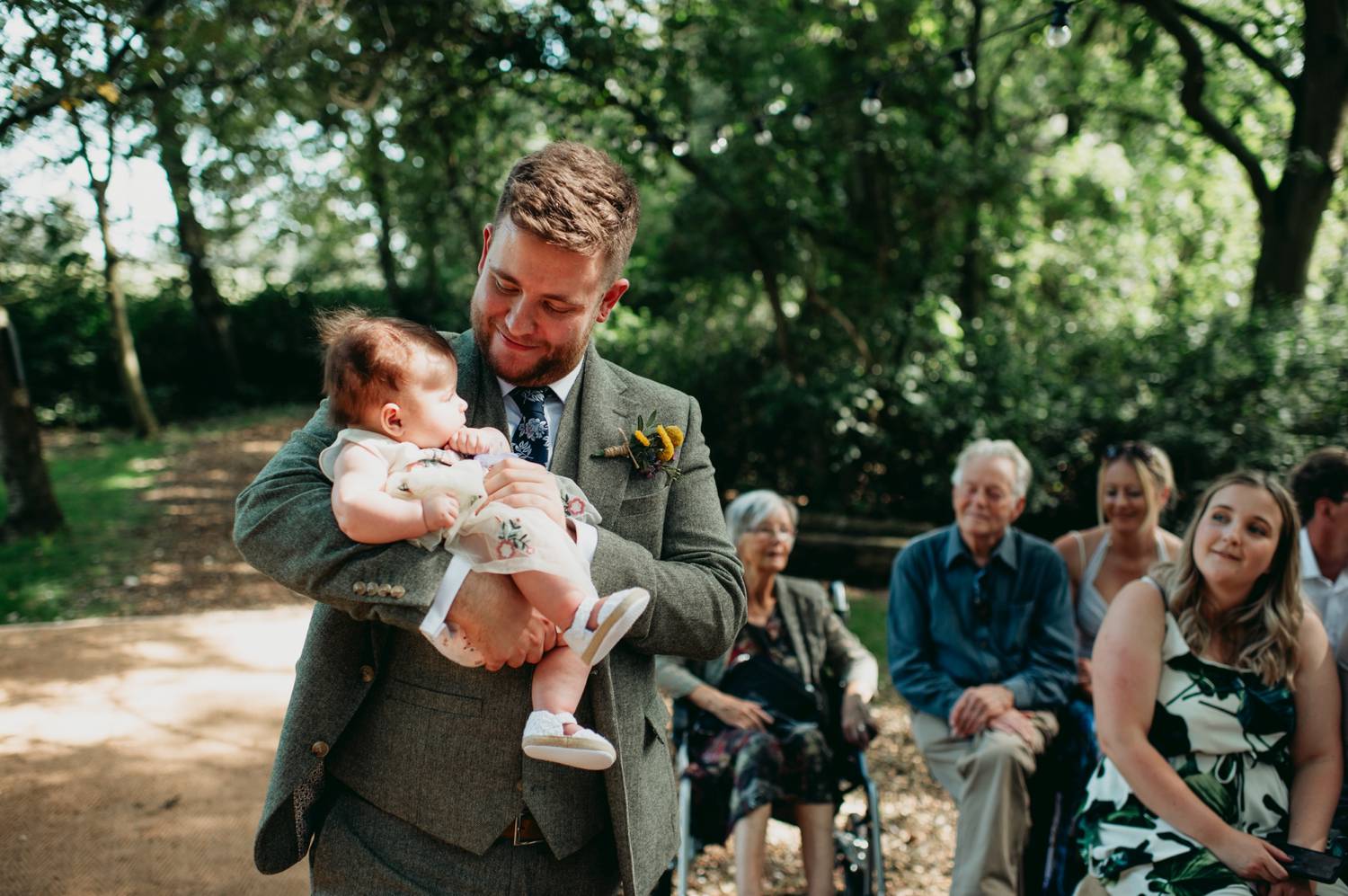 Grooms holds baby flower girl