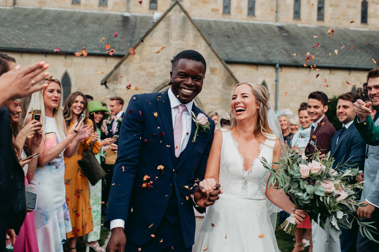 Bride and groom exit church under flower petals