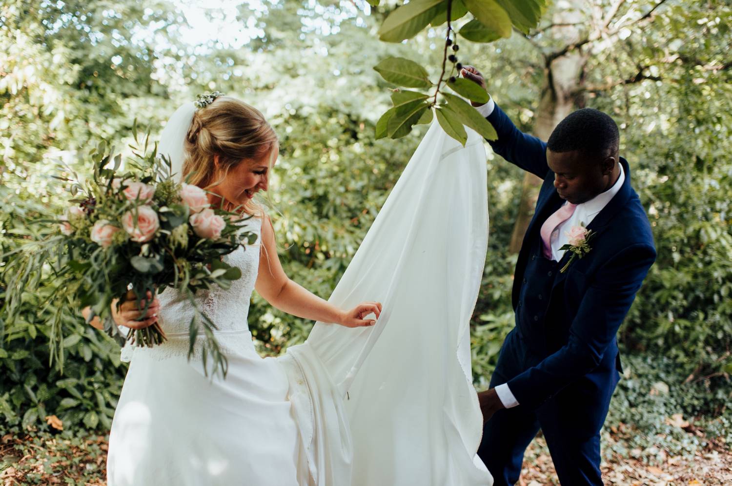 Groom helps bride with train of dress