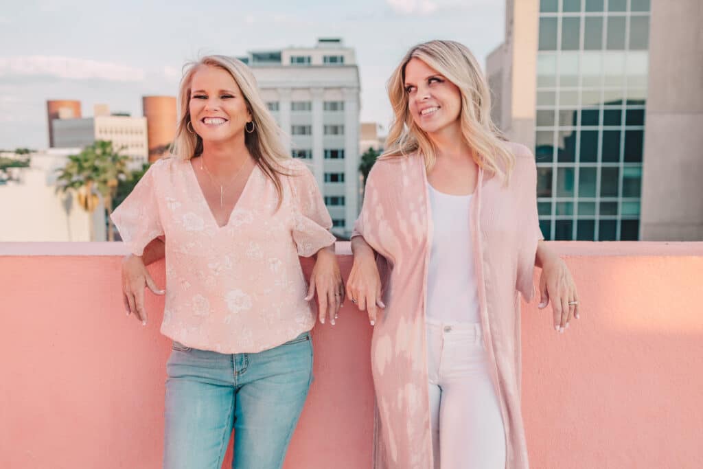 two women in front of pink wall