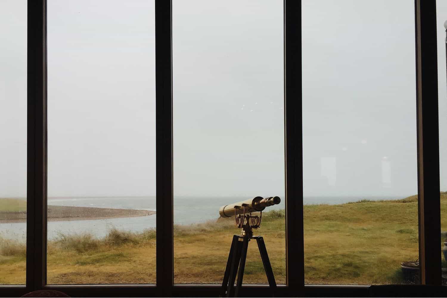 telescope looking through a window over the sea