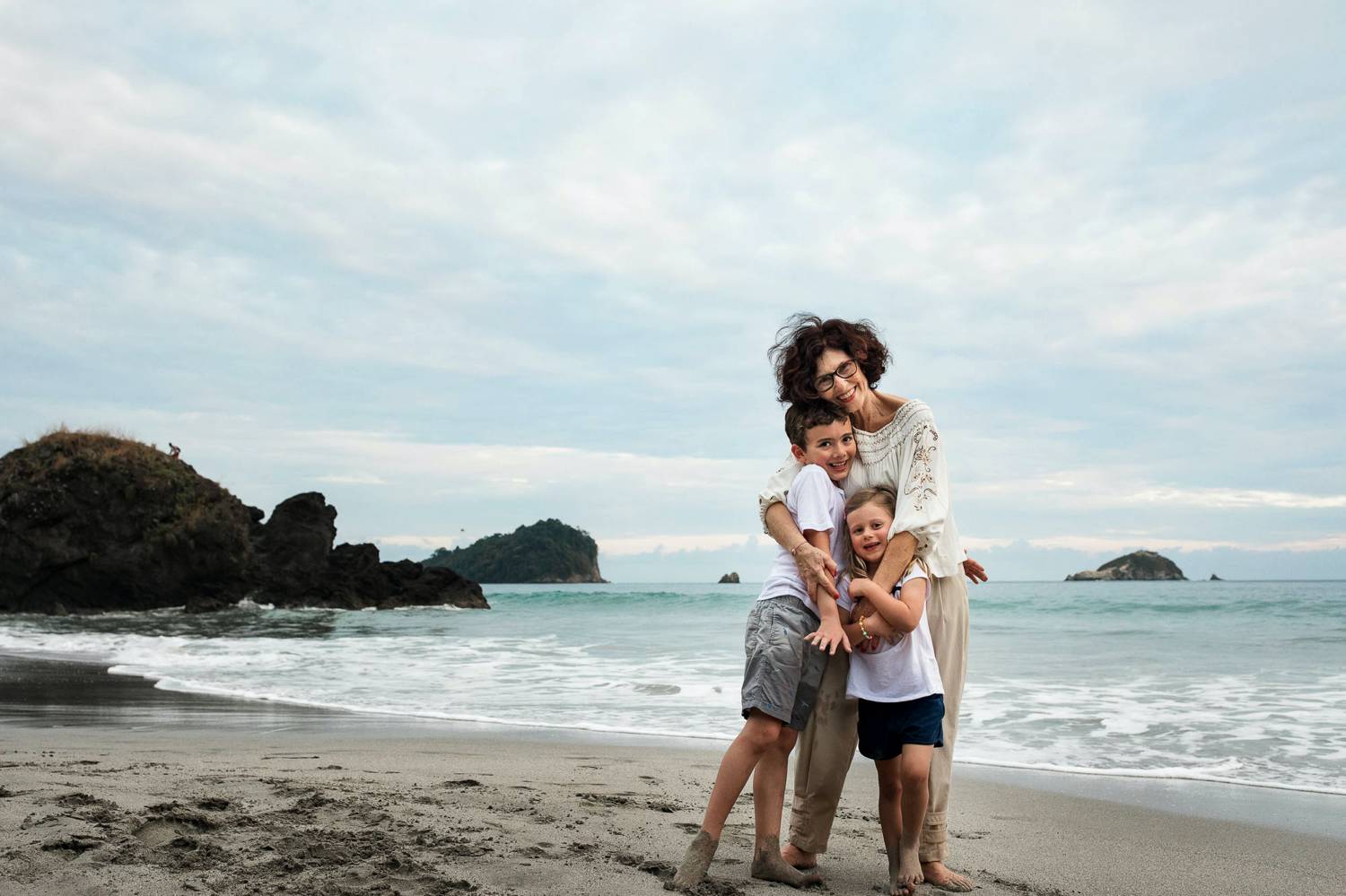 A photo of Kevin Heslin depicts a curly-haired mom on a beach holding her sons.