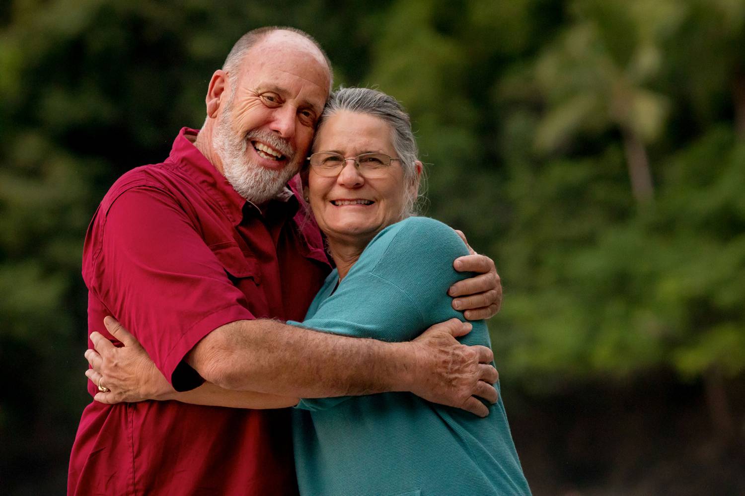 A photo by Kevin Heslin depicts a gray-bearded man with his arms wrapped around his silver-haired partner.