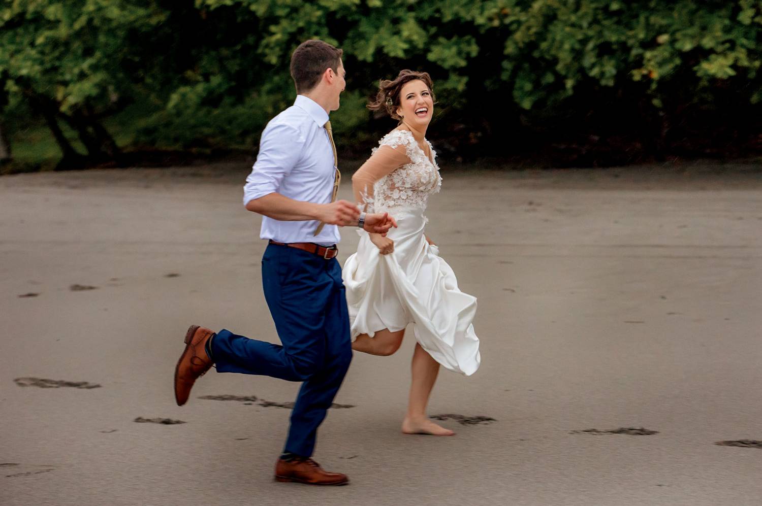 Client Experience: A photo by Kevin Heslin depicts a bride and groom running along a beach in their wedding clothes.