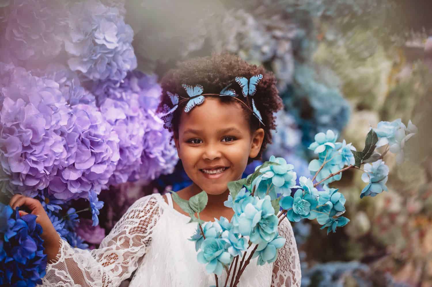 Portrait photography of little girl among silk flowers in a Michael's Craft Store for a photo project.