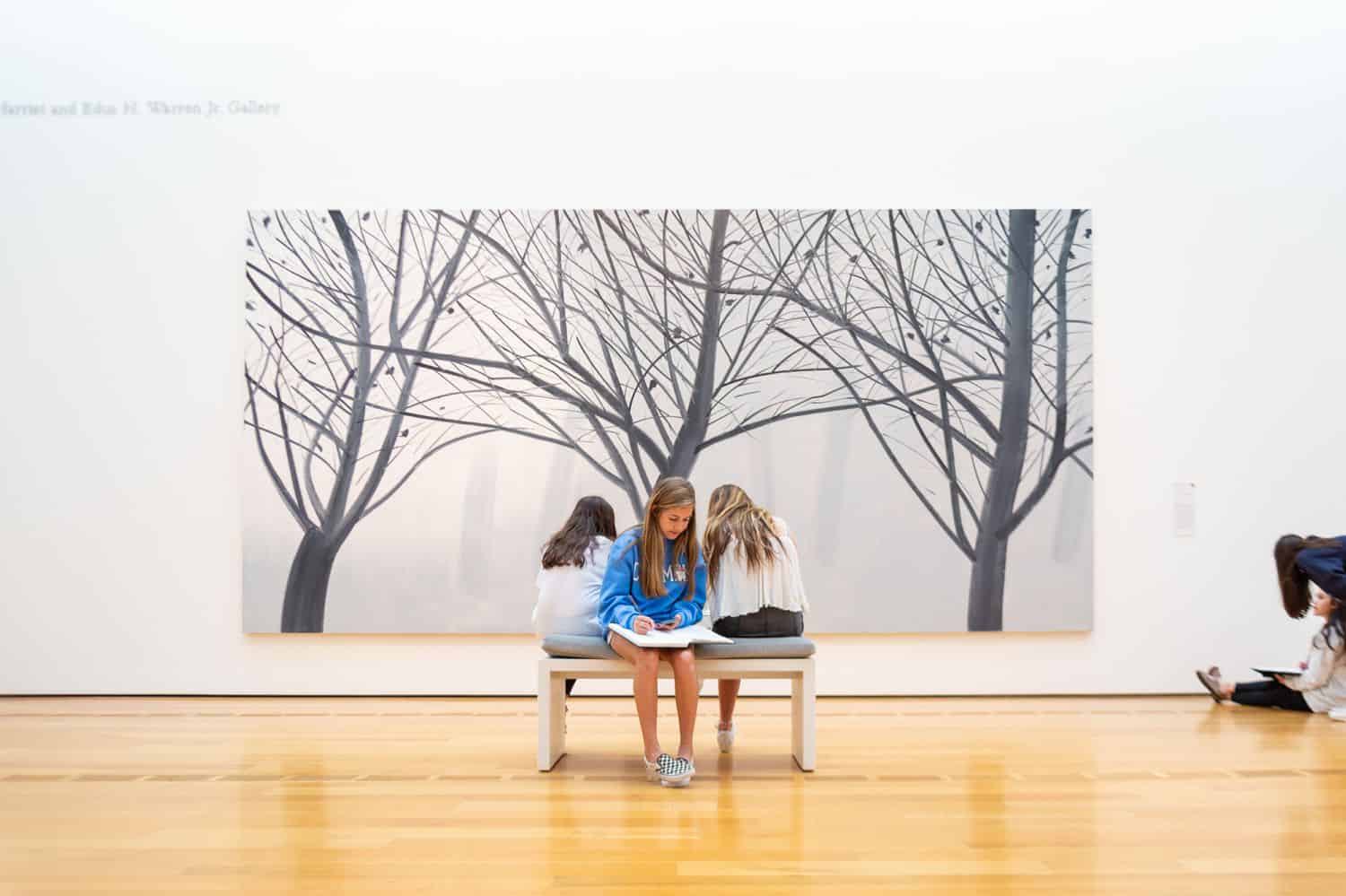 Build Your Dream Photography Business on a Budget: Three schoolgirls sit on a bench in front of a massive gallery painting