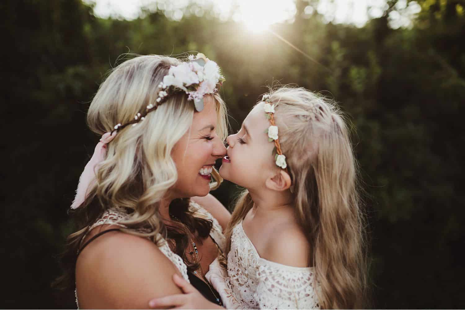 mother and daughter rub noses wearing white lace dresses