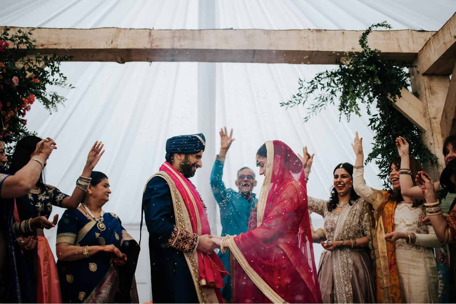 Wedding Print Packages: An Indian bride and groom stand in a shower of rice at the end of their wedding ceremony.